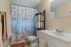 Full bathroom featuring toilet, tile patterned floors, vanity, and shower / bath combination with curtain