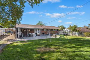 Back of house with a yard and a patio area