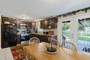 Kitchen featuring dark brown cabinets, black appliances, french doors, and a textured ceiling