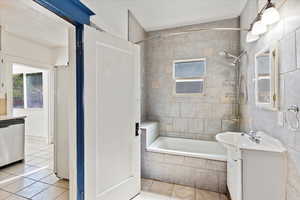 Bathroom featuring tile patterned floors, vanity, and tiled shower / bath