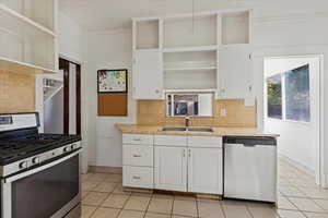 Kitchen featuring white cabinets, sink, tasteful backsplash and tile countertops