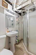 Bathroom featuring tile patterned flooring, a shower with door, and toilet