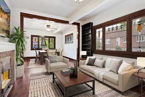 Living room with ceiling fan, beam ceiling, wood-type flooring, a brick fireplace, and crown molding