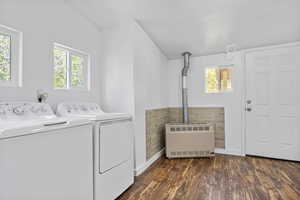 Clothes washing area featuring washer and clothes dryer, heating unit, and dark hardwood / wood-style floors