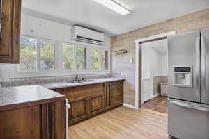 Kitchen featuring stainless steel fridge, sink, a wall mounted AC, light hardwood / wood-style floors, and a healthy amount of sunlight