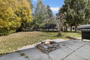 View of yard with a trampoline, a patio area, and an outdoor fire pit