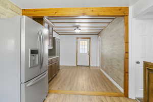 Kitchen with brick wall, stainless steel fridge with ice dispenser, and light wood-type flooring