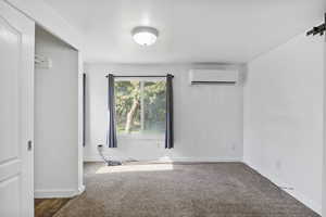 Spare room featuring an AC wall unit, carpet floors, and a barn door