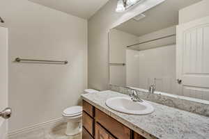 Bathroom featuring vanity, tile patterned flooring, toilet, and a shower