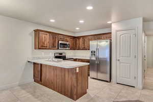 Kitchen with light tile patterned floors, sink, appliances with stainless steel finishes, and kitchen peninsula