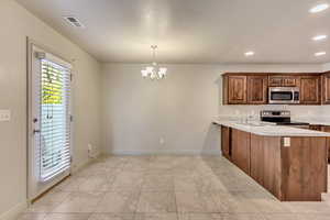 Kitchen with a chandelier, pendant lighting, sink, kitchen peninsula, and appliances with stainless steel finishes