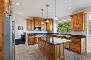 Kitchen featuring pendant lighting, a kitchen island, sink, stainless steel appliances, and a textured ceiling