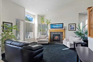 Carpeted living room featuring a towering ceiling, a high end fireplace, and a wealth of natural light