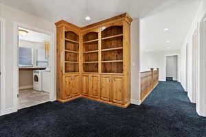 Hall featuring washing machine and clothes dryer and dark carpet