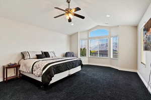 Carpeted bedroom featuring ceiling fan and lofted ceiling