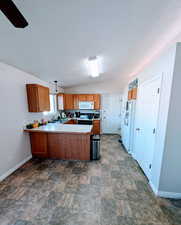 Kitchen featuring white appliances, sink, kitchen peninsula, hanging light fixtures, and lofted ceiling