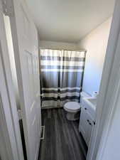 Bathroom with vanity, toilet, curtained shower, and hardwood / wood-style floors