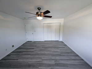 Unfurnished bedroom featuring a closet, ceiling fan, and dark hardwood / wood-style flooring