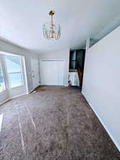 Interior space with a chandelier, vaulted ceiling, carpet floors, and a textured ceiling