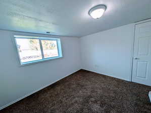 Carpeted empty room featuring a textured ceiling