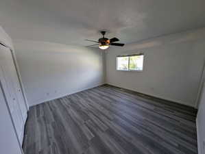 Unfurnished bedroom featuring a closet, ceiling fan, and dark hardwood / wood-style flooring