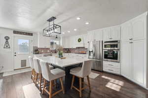 Kitchen featuring white cabinets, a kitchen island, stainless steel appliances, and decorative backsplash