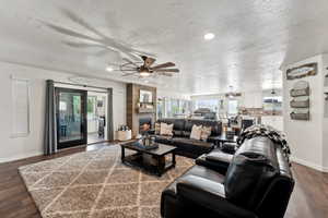 Open Living room featuring a fireplace, ceiling fan, dark hardwood floors