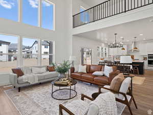 Family room with light hardwood / wood-style flooring, a chandelier, and a high ceiling