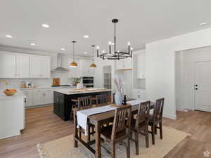 Interior space featuring white cabinets, wall chimney exhaust hood, pendant lighting, and a kitchen island