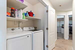 Washroom with independent washer and dryer and light hardwood / wood-style flooring