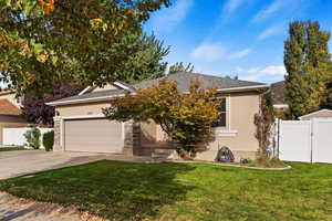 View of property hidden behind natural elements featuring a garage and a front yard