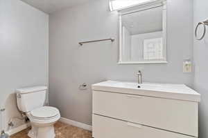 Bathroom featuring a textured ceiling, tile patterned floors, vanity, and toilet