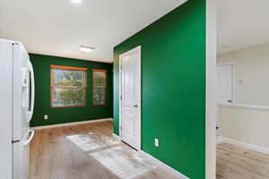 Unfurnished bedroom featuring white fridge with ice dispenser and light wood-type flooring