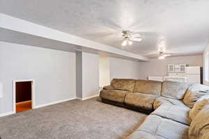 Living room with carpet flooring, a textured ceiling, and ceiling fan