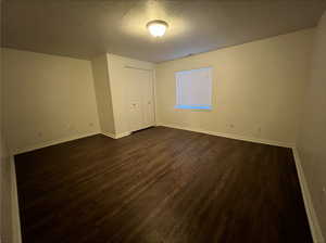 Unfurnished room with a textured ceiling and dark hardwood / wood-style flooring