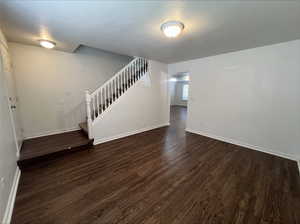 Unfurnished living room featuring a textured ceiling and dark hardwood / wood-style flooring