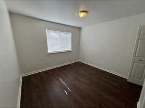 Empty room with dark hardwood / wood-style flooring