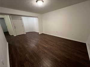 Spare room with a textured ceiling and dark hardwood / wood-style flooring