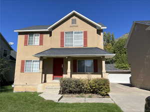 View of front facade with covered porch, a front yard, and a garage