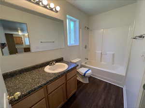 Full bathroom with shower / bathing tub combination, wood-type flooring, vanity, and toilet