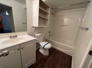 Full bathroom featuring wood-type flooring, vanity, toilet, and washtub / shower combination