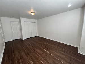 Unfurnished bedroom featuring a textured ceiling, a closet, and dark wood-type flooring