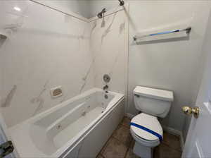 Bathroom with shower / bathing tub combination, tile patterned floors, and toilet