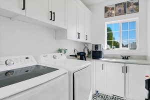 Washroom featuring washer and clothes dryer, sink, and cabinets