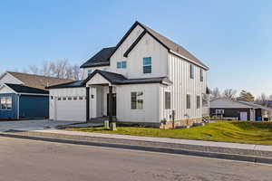 Modern farmhouse style home featuring a garage and a front lawn