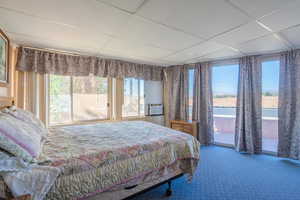 Bedroom with a paneled ceiling, carpet, and access to outside