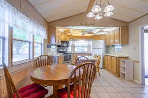 Dining room with lofted ceiling, a chandelier, sink, and light tile patterned floors