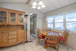 Tiled dining room with a chandelier and lofted ceiling with beams