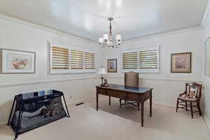 Carpeted office featuring ornamental molding, an inviting chandelier, and a wealth of natural light