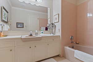 Bathroom featuring tiled shower / bath, vanity, and crown molding